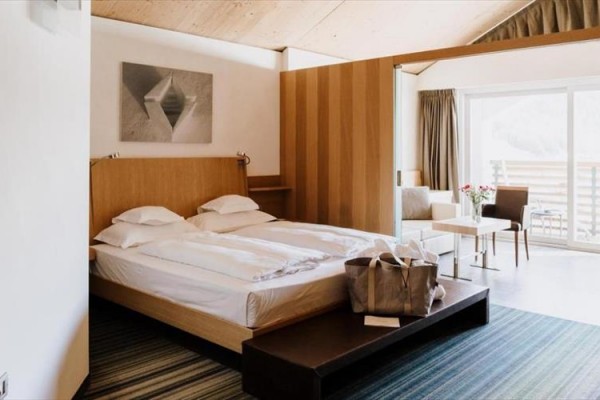 Elegancki pokój hotelowy z podwójnym łóżkiem, sofą i balkonem.