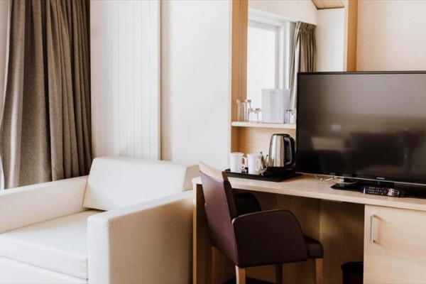 Nowoczesny pokój hotelowy z telewizorem, biurkiem i sofą.