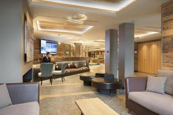 Nowoczesna recepcja hotelowa z wygodnymi sofami i dekoracyjnym kominkiem.