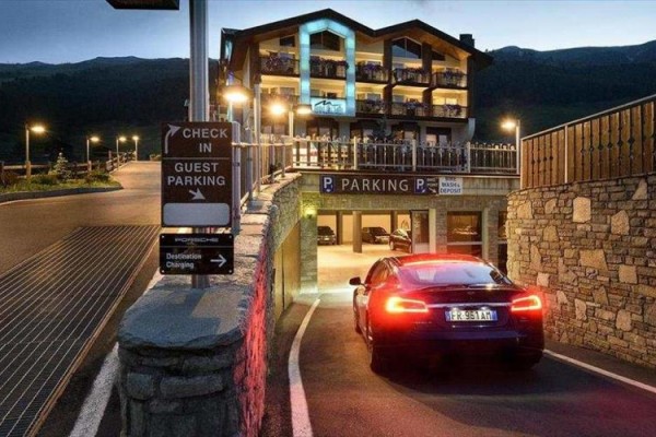 Niebieski samochód wjeżdża do podziemnego garażu hotelu przy wieczornym świetle.
