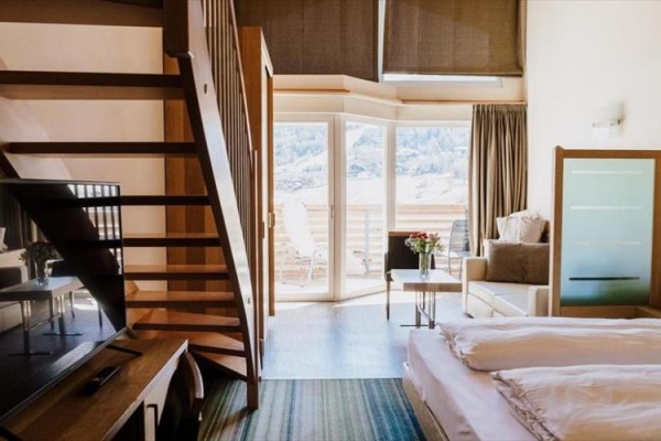 Pokój hotelowy z piętrowymi schodami i widokiem na góry.