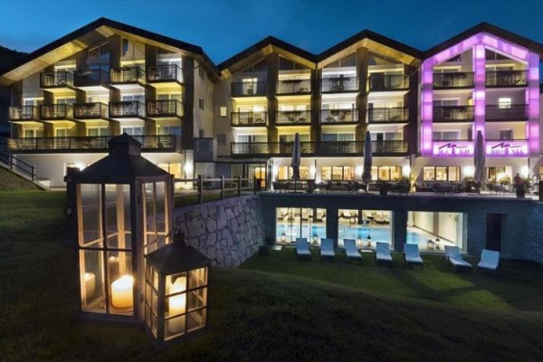 Nowoczesny hotel z podświetlonymi fasadami i latarniami w ogrodzie o zmierzchu.