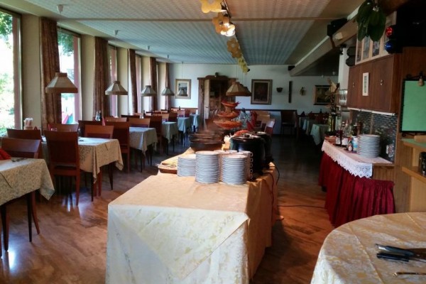Restauracja z nakrytymi stołami i stołem bufetowym pośrodku.
