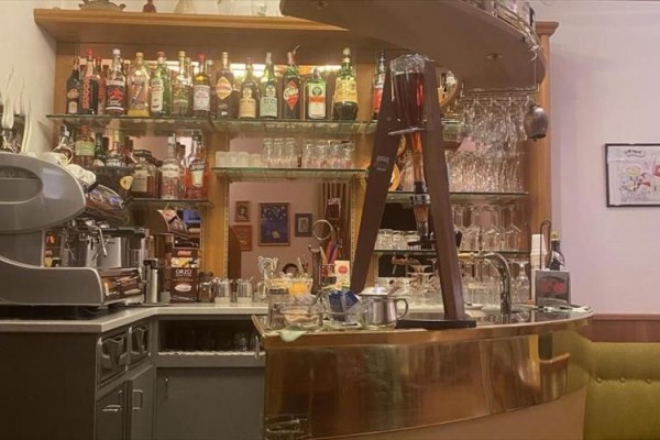 Barowy blat z butelkami alkoholu, ekspresem do kawy i szklankami.