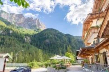 Hotel z balkonem w górskim krajobrazie z sosnami i niebieskim niebem.