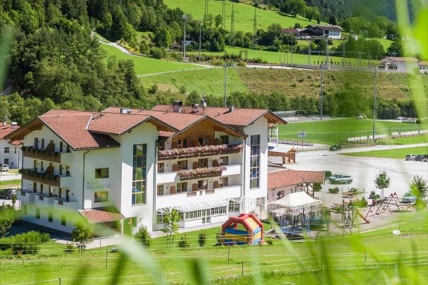Budynek hotelu otoczony zielonym krajobrazem z lasami i placem zabaw.