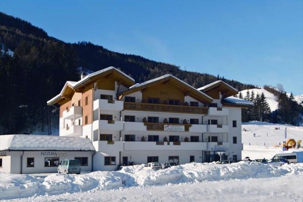 Budynek hotelu z drewnianymi balkonami w zaśnieżonym krajobrazie przy lesie.