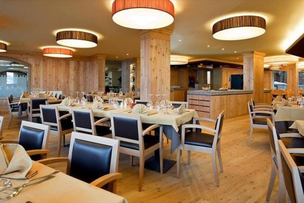 Restauracja z drewnianym wnętrzem i nakrytymi stołami.