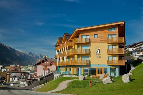 Nowoczesny hotel z drewnianymi balkonami na zboczu górskim.