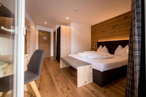 Nowoczesny pokój hotelowy z drewnianymi elementami i łóżkiem małżeńskim.