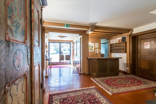 Recepcja hotelowa z drewnianym blatem i dywanem na podłodze.
