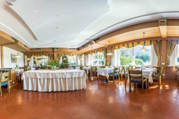 Elegancka restauracja z przestronnym układem stołów i dużymi oknami z widokiem na naturę.