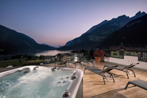 Jacuzzi na tarasie na dachu z widokiem na góry i jezioro o zmierzchu.