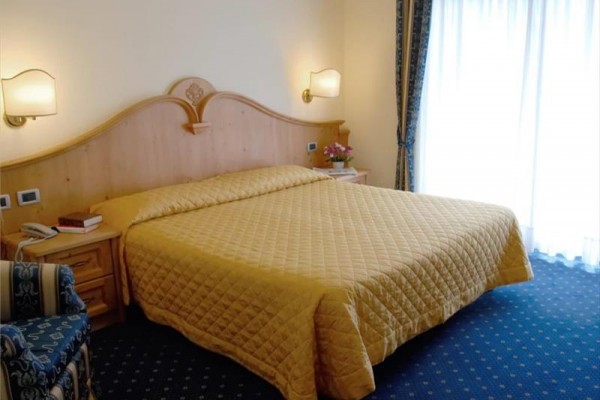 Pokój hotelowy z łóżkiem małżeńskim i drewnianymi meblami.