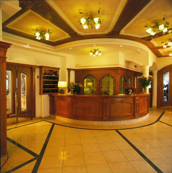 Recepcja hotelu z drewnianym blatem i kwiatową dekoracją.