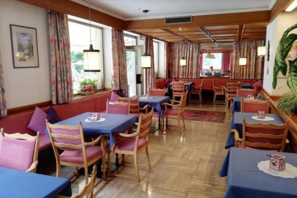 Restauracja z drewnianymi meblami i niebieskimi obrusami na stołach.