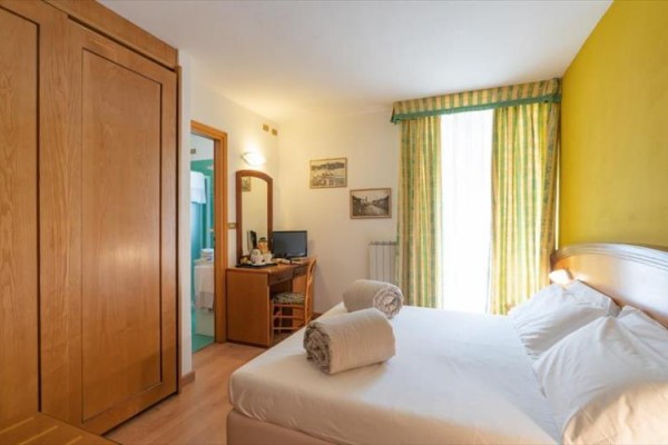 Pokój hotelowy z łóżkiem małżeńskim, biurkiem i szafą.