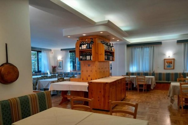 Restauracja z drewnianymi meblami i wyeksponowanymi butelkami wina na stojaku.