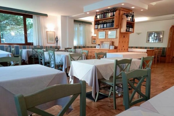 Restauracja z drewnianymi krzesłami i stołami z białymi obrusami.