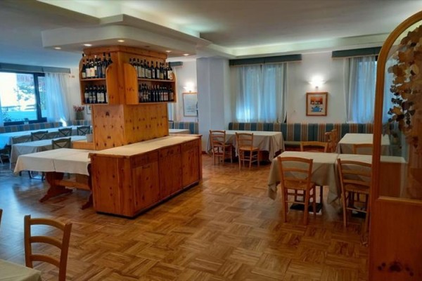 Restauracja z drewnianymi meblami i butelkami wina na półkach.  