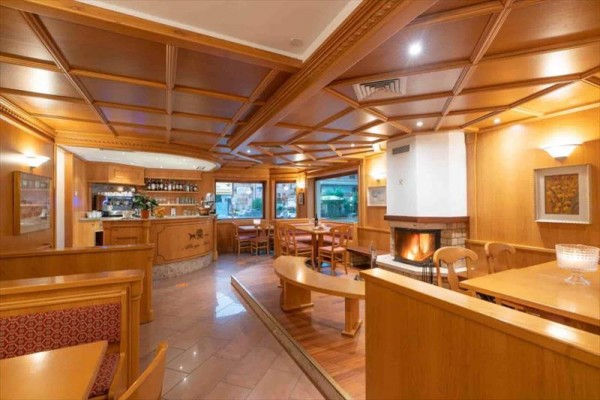 Wnętrze restauracji z drewnianą boazerią i kominkiem.
