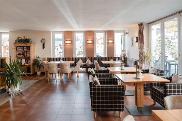 Przestronna restauracja z drewnianymi meblami i dużymi oknami.