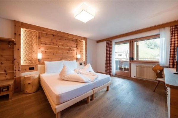 Pokój hotelowy z drewnianymi meblami, podwójnym łóżkiem i dużym oknem.