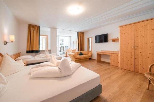 Przestronny pokój hotelowy z dwoma łóżkami, kanapą, szafą i telewizorem.