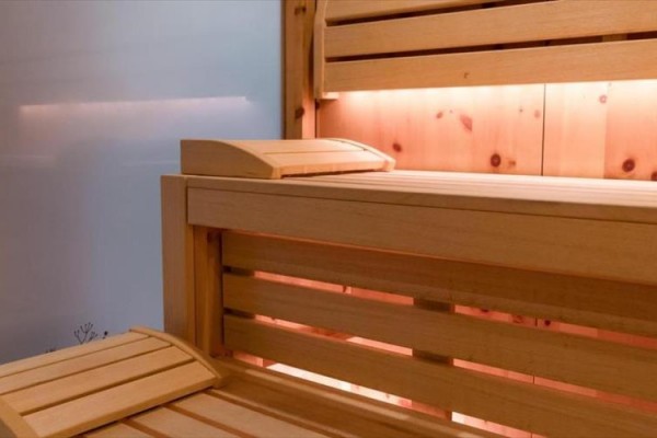 Drewniana sauna z ławkami i delikatnym oświetleniem.