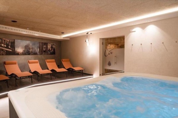 Strefa wellness z jacuzzi i pomarańczowymi leżakami.