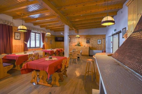 Wnętrze drewnianej restauracji z czerwonymi obrusami i drewnianymi meblami.