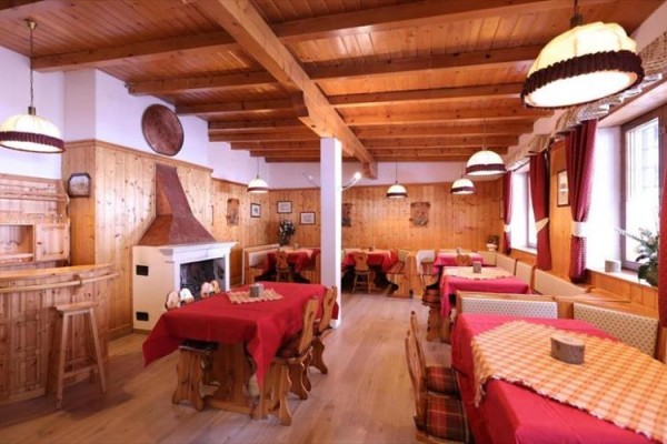 Wnętrze restauracji wyłożonej drewnem z kominkiem i czerwonymi obrusami.