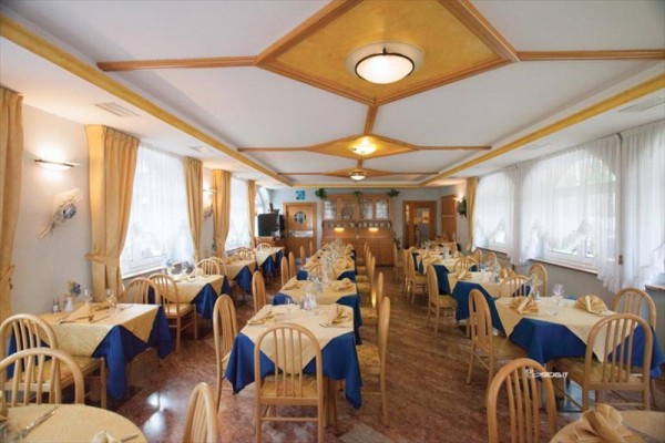 Restauracja z nakrytymi stołami i drewnianymi krzesłami, udekorowana niebiesko-żółtymi obrusami.