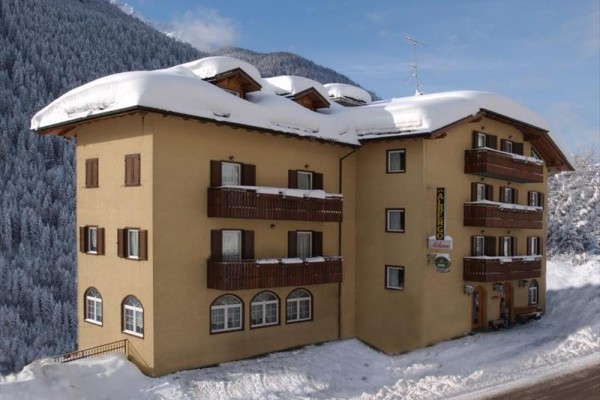 Górski hotel z drewnianymi balkonami pokryty śniegiem przy lesie.