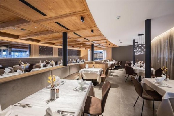 Nowoczesna restauracja z drewnianym sufitem i nakrytymi stołami.
