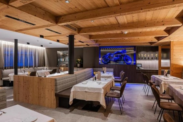Stylowa restauracja z drewnianym wnętrzem i wystawionym motocyklem w niebieskim oświetleniu.