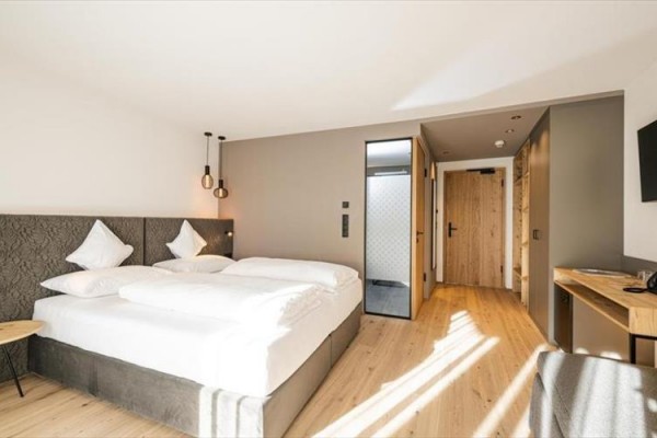 Nowoczesny pokój hotelowy z podwójnym łóżkiem i drewnianą podłogą.