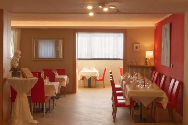 Wnętrze eleganckiej restauracji z czerwonymi krzesłami i nakrytymi stołami.