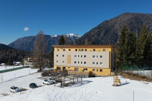 Budynek hotelu na zaśnieżonym terenie z górami w tle.