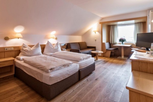 Pokój hotelowy z podwójnym łóżkiem, biurkiem i miejscem do siedzenia przy oknie.