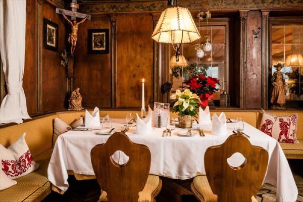 Przy stole w rustykalnej restauracji uroczyście nakryty stół z kwiatami i świecą.