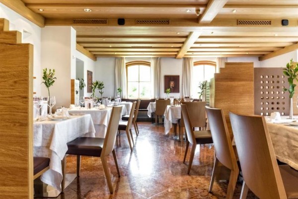 Elegancka restauracja z drewnianym wnętrzem i nakrytymi stołami.