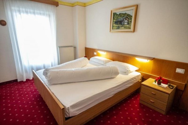 Pokój hotelowy z łóżkiem małżeńskim i stolikiem nocnym.