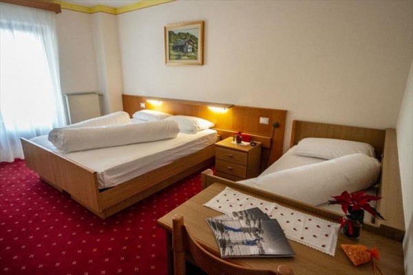 Pokój hotelowy z łóżkiem małżeńskim i pojedynczym, wyposażony w meble i dekoracje.