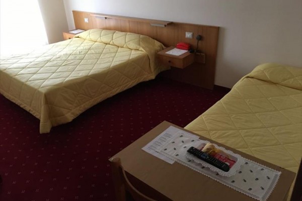Dwa jednoosobowe łóżka z żółtymi narzutami w pokoju hotelowym z czerwonym dywanem.