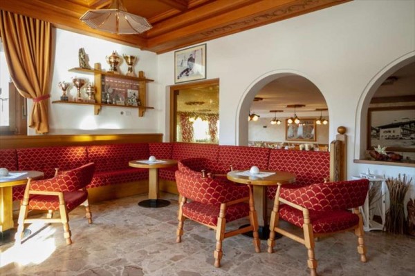 Restauracja z czerwonymi obiciami siedzeń i pucharami na półkach.