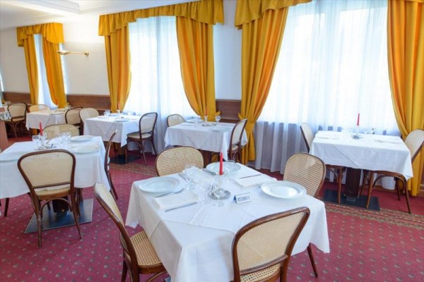 Restauracja z białymi obrusami i żółtymi zasłonami.