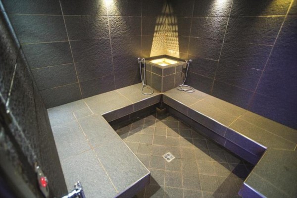Sauna parowa z ciemną okładziną i kamiennymi ławkami.