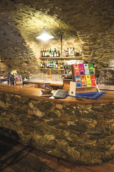 Kamienny bar z butelkami alkoholu i ekspresem do kawy w rustykalnej piwnicy.