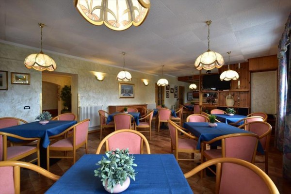 Restauracja z niebieskimi obrusami, różowymi krzesłami i wiszącymi lampami.